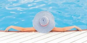 woman leaning on white concrete surface beside swimming pool during daytime