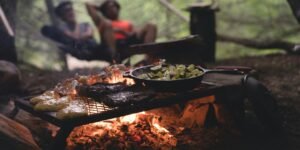 selective focus photo of skillet and meat on top of grill with fire